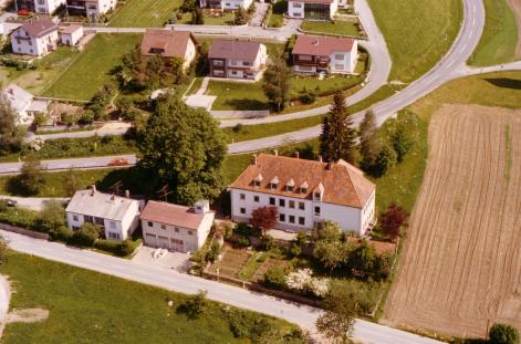 Luftaufnahme von Krinning mit Schulhaus, Lehrerwohnhaus und Schulhof 1996. Foto von Herrn Siegert, Archiv Schule